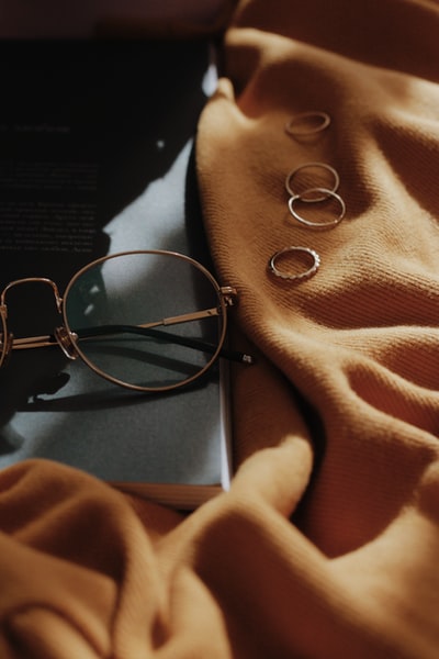 灰色框眼镜靠近四个铜色配件在橙色床单上